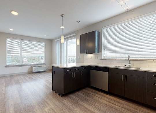 A kitchen with dark wood floors and white walls.