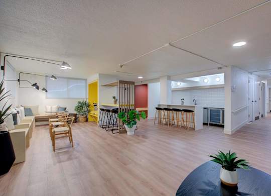 A community lounge with a couch, chairs, and a kitchen.