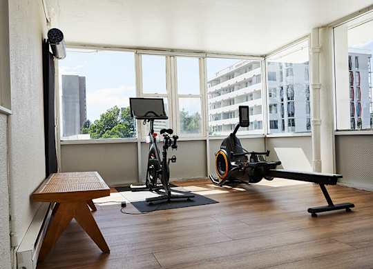 A light-filled room with a stationary bike and a rowing machine.