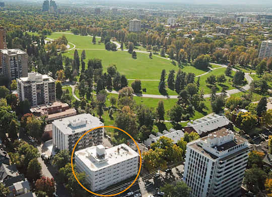 An aerial view of a city with a large white building circled in the middle.