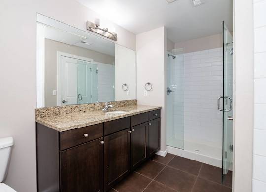 A bathroom with a sink, mirror, and shower.