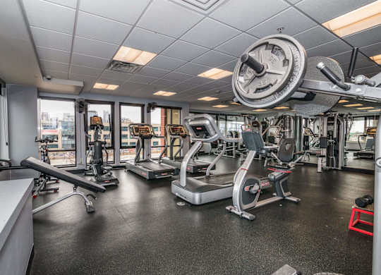 A gym with a variety of equipment including treadmills, weights, and exercise machines.