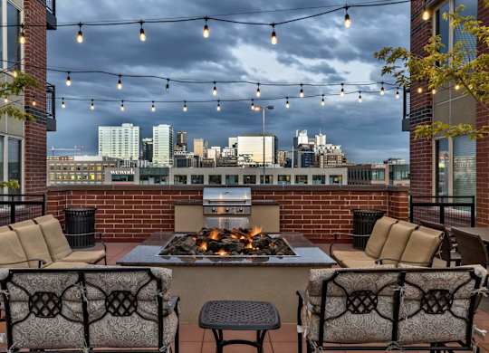 A patio with a fire pit and chairs.