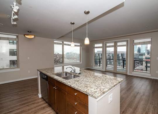 A kitchen with a granite countertop and wooden floors.