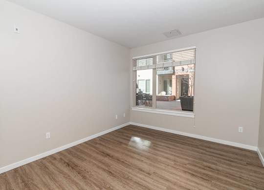 A room with wooden flooring and a window showing an outdoor scene.