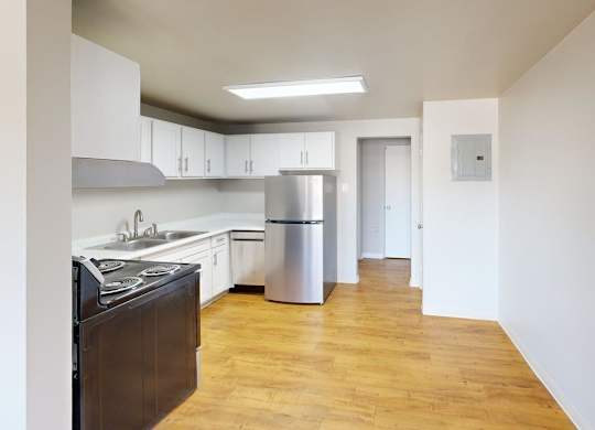 A kitchen with a stove, sink, and cabinets.