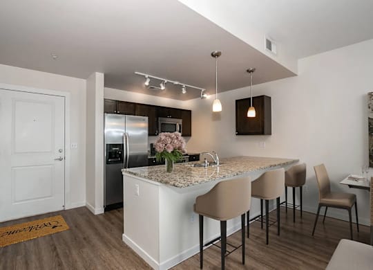 A kitchen with a white island and brown chairs.