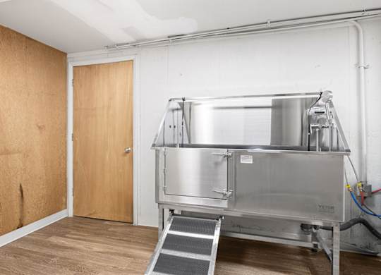 A large metal stainless steel tank in a room with a wooden door.