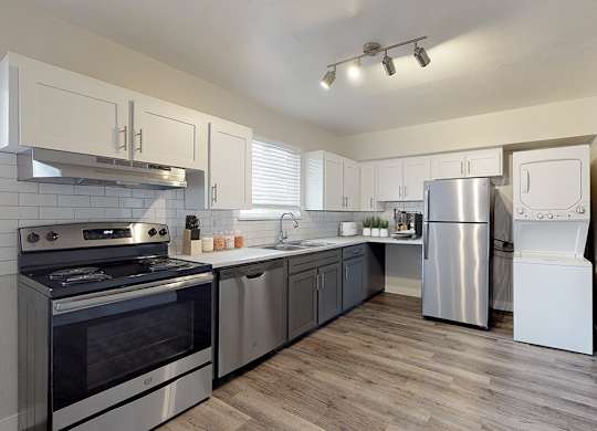 A modern kitchen with stainless steel appliances and wooden floors.