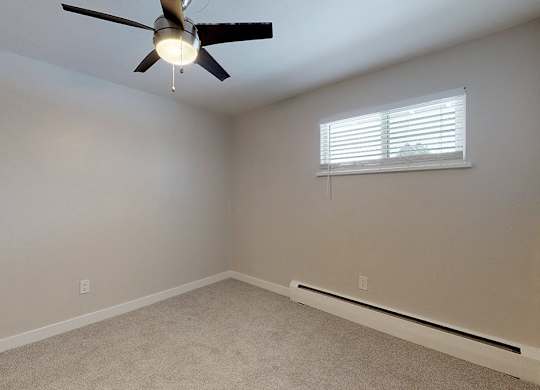 A room with a ceiling fan and a window with blinds.