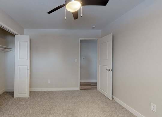 A room with a ceiling fan and two doors.