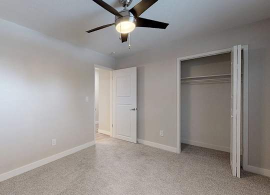 A room with a ceiling fan and a door.