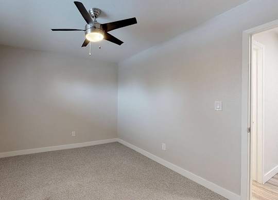 A room with a ceiling fan and carpeted floor.