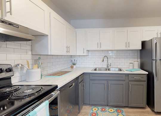 A kitchen with a stove, sink, and refrigerator.