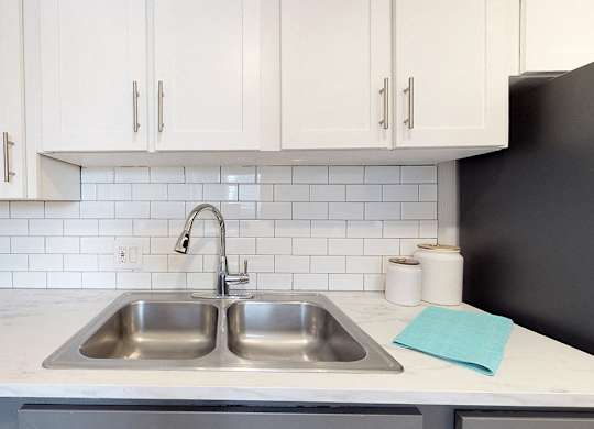 A kitchen with a white countertop and a black refrigerator.