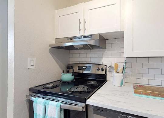 A kitchen with a stove and a white counter.