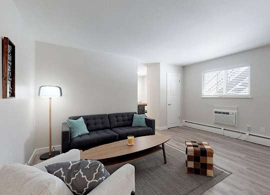 A living room with a black couch and a grey ottoman.