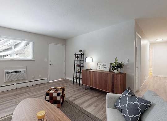 A living room with a couch, a coffee table, and a window with blinds.