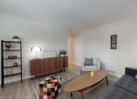 A living room with a black couch, a wooden coffee table, and a wooden bookshelf.