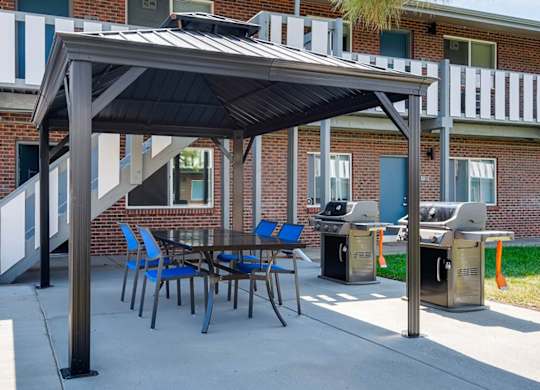 A patio with a table and chairs under a roof.