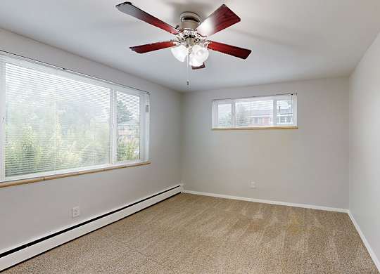 A room with a ceiling fan and a window with blinds.