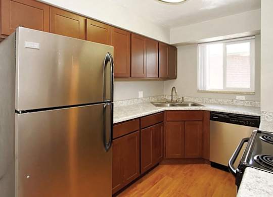 A kitchen with a stainless steel refrigerator and wooden cabinets.