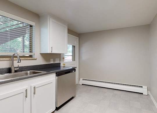 A kitchen with white cabinets and a black countertop.