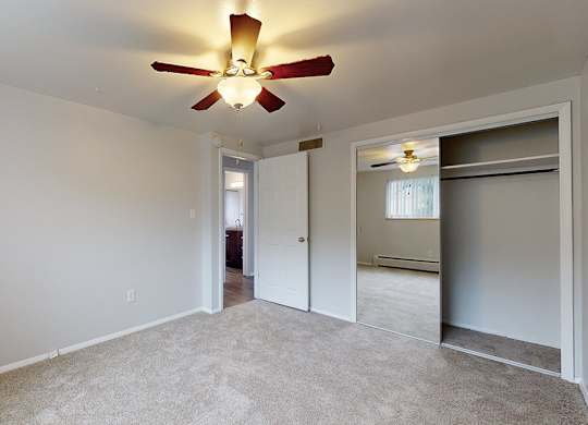 A room with a ceiling fan and carpeted floor.