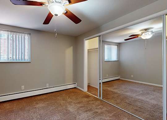 A room with a ceiling fan and a window with blinds.