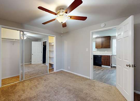 A room with a ceiling fan and carpeted floor.