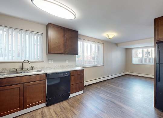 A kitchen with a black fridge and wooden cabinets.