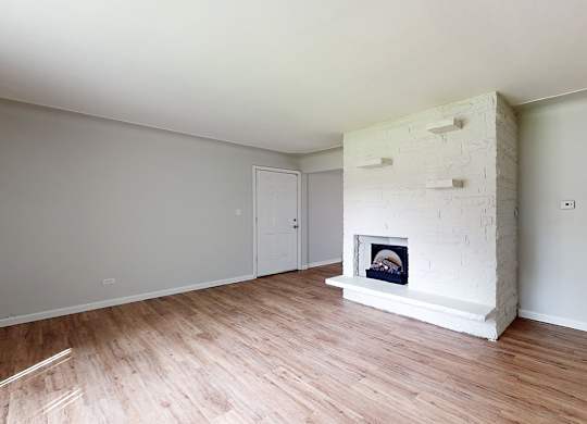 A white room with a fireplace and wooden floors.