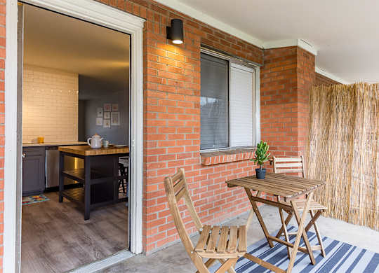 A wooden chair is placed in front of a small table with a plant on it.