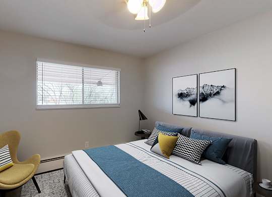 A bedroom with a bed, chair, and pictures on the wall.