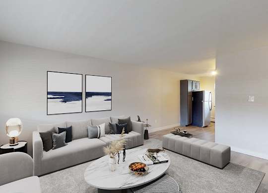A modern living room with a grey couch, a white coffee table, and a painting on the wall.