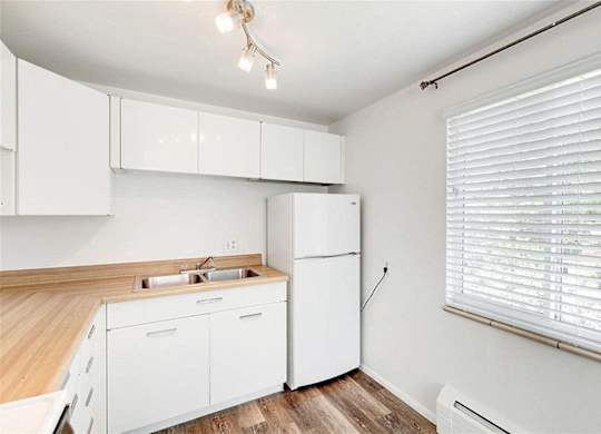 A white kitchen with a wooden counter top and white cabinets.