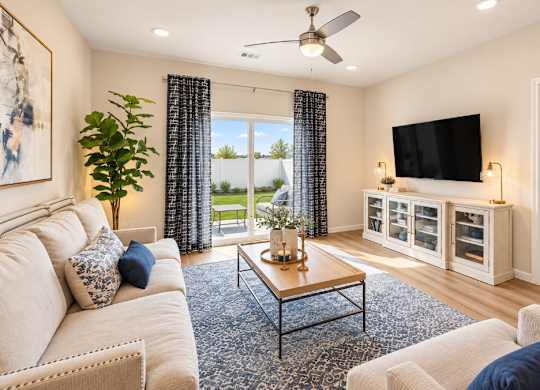 A living room with a white couch, a coffee table, and a flat screen TV mounted on the wall.