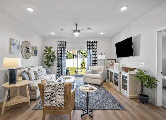 A well-lit living room with a white sofa, a wooden chair, and a ceiling fan.