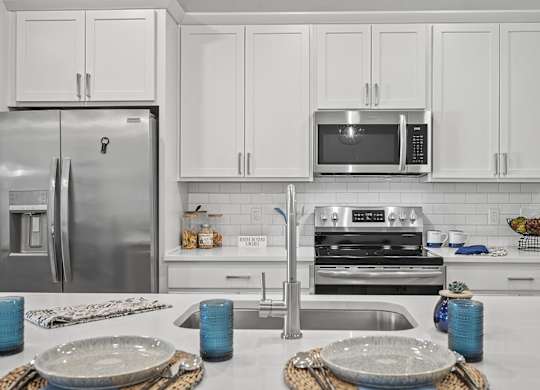 A modern kitchen with a stainless steel refrigerator, microwave, and oven.