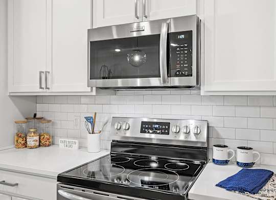 A modern kitchen with a stove top oven and microwave above it.