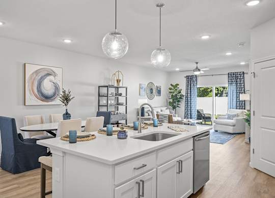 A modern kitchen with a dining area and a living room in the background.
