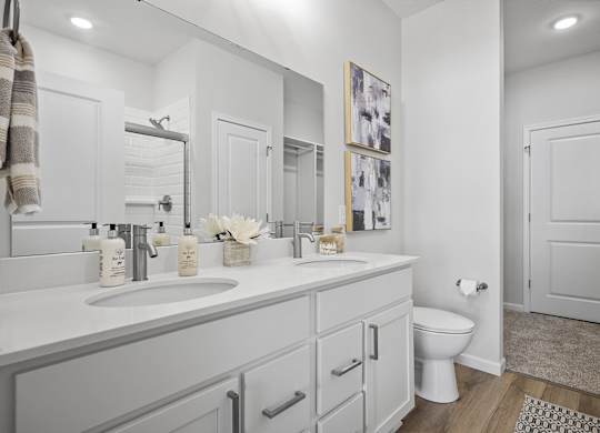 A bathroom with a toilet, sink, and mirror.