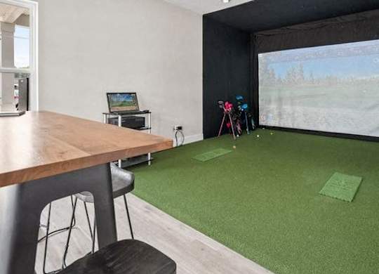 A room with a large screen and a desk with a computer.