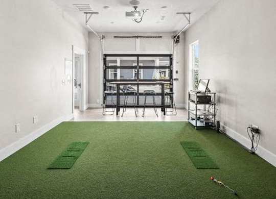 A room with a green carpet and a long table with chairs.