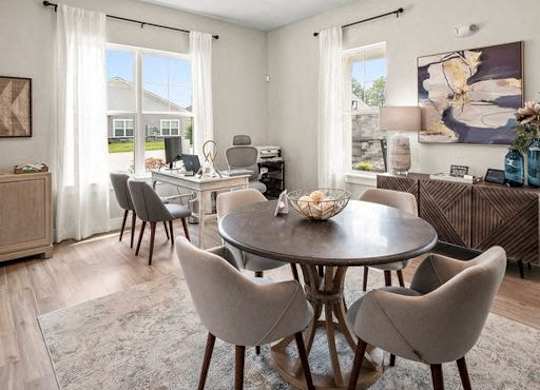 A dining room with a round table and grey chairs.