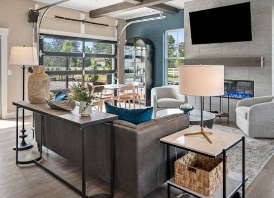 A modern living room with a grey sofa, a wooden coffee table, and a large flat screen TV mounted on the wall.