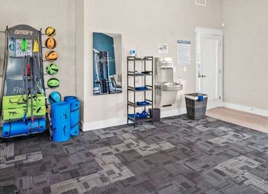 A room with a treadmill, exercise equipment, and a basket.