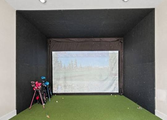 A room with a green carpet and a screen on the wall.