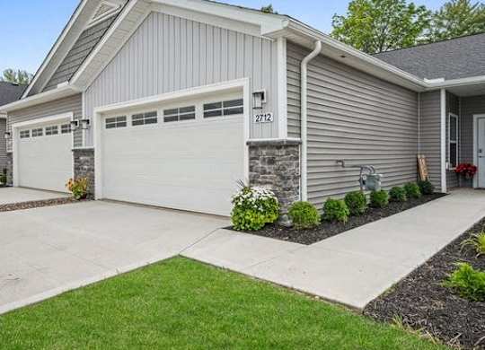A house with a grey siding and a white garage door.