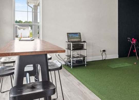 A room with a wooden table and chairs, a laptop, and a camera on a tripod.